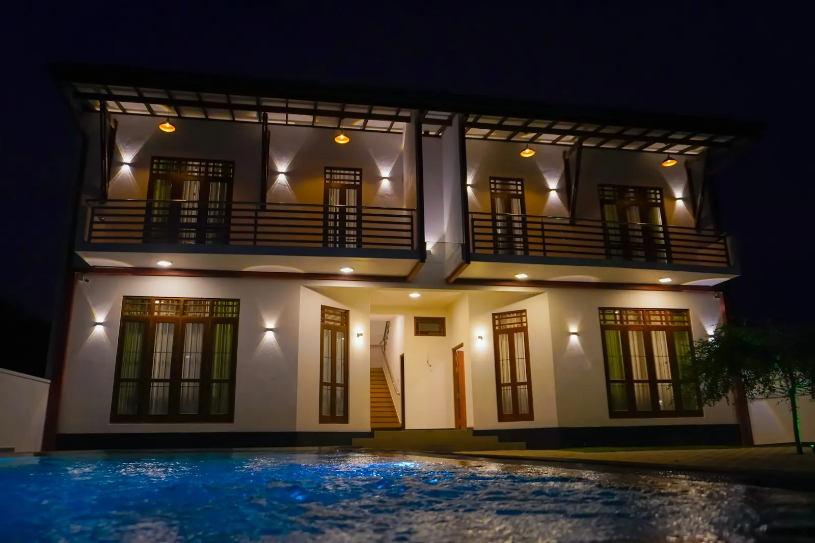 Two-storey home lit at night with pool (sample image)